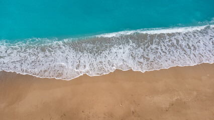 Aerial view of beautiful sandy beach and soft turquoise ocean wave. Tropical sea in summer season on Megali Petra beach on Lefkada island.