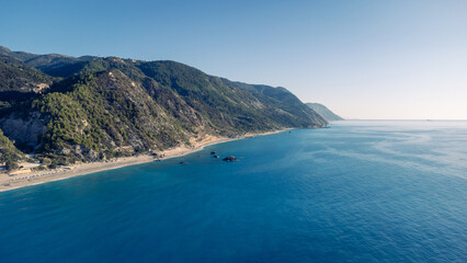 Aerial view of beautiful sandy beach with sunshades and soft turquoise ocean wave. Tropical sea in summer season on Kathisma beach on Lefkada island.