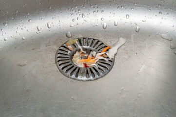 sink drain with stuck garbage. dirty metal sink