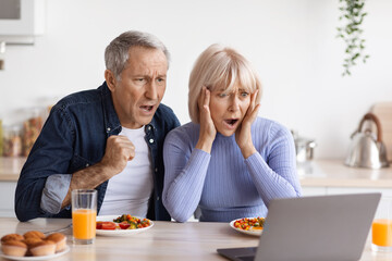 Shocked senior couple looking at laptop screen