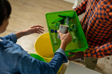 High angle view of multiracial coupe collecting bottles and can in container at home