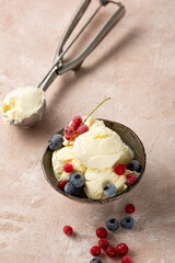 Ice cream scoops in bowl and frozen berries