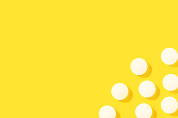 Pelotas de ping-pong blanca proyectando sombra sobre un fondo amarillo brillante liso y aislado. Vista superior. Copy space