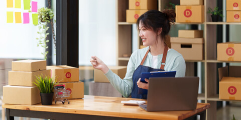 A portrait of Asian woman, e-commerce employee freelance with parcel box for deliver to customer. Online marketing packing box delivery concept.