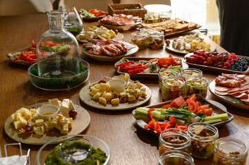 A table with various snacks, fruits, vegetables, cheeses, sausages.