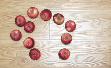 Fresh red apples lie on a wooden textured floor forming a frame for placing text. 