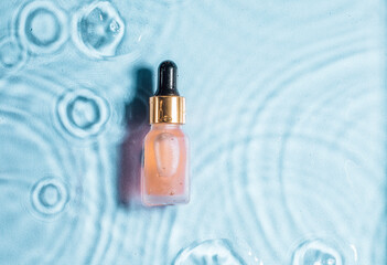 Cosmetic spa medical skincare, glass serum bottle with collagen on blue water background with waves. Advertising of medical product for anti-aging care, moisturizing