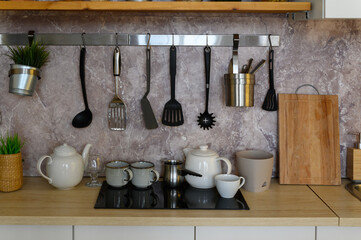 electric stove, built-in oven, cooking utensils. Wooden kitchen in the apartment with a modern interior and new furniture