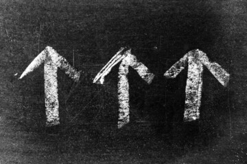 White chalk drawing as arrow shape on black board background