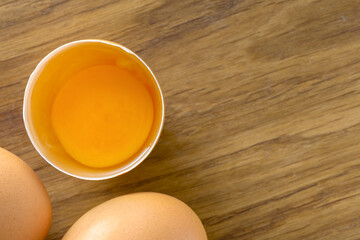 Broken brown raw egg whole eggs wooden background top view