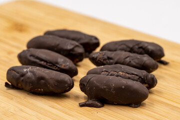 Special chocolate with dark outside and coconut inside. Dark chocolate with coconut filling on a wooden background. close up