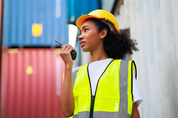 Black female dock worker control loading containers box from cargo at warehouse container yard....