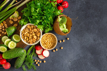 Different vegetables, greenery, legumes and nuts on dark background top view. Healthy food clean eating concept