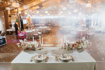Banquet table is decorated with plates, cutlery, glasses, candles and flower arrangements