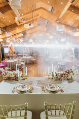 Banquet table is decorated with plates, cutlery, glasses, candles and flower arrangements