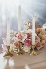 Banquet table is decorated with plates, cutlery, glasses, candles and flower arrangements