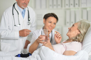 Obraz premium Senior woman in hospital with caring doctors