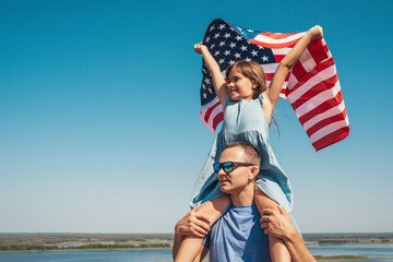 Happy family father and child with USA flag enjoy nature. The concept of freedom