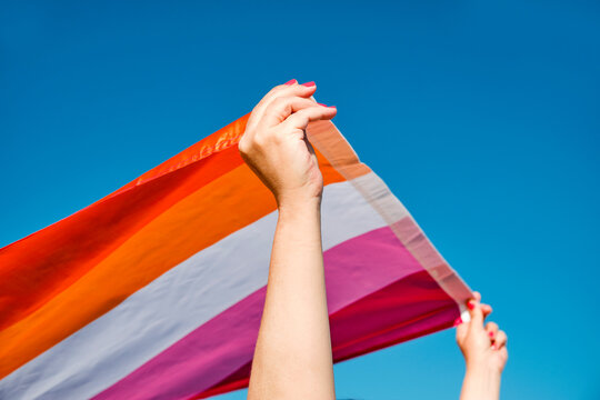 woman waving a lesbian pride flag outdoors