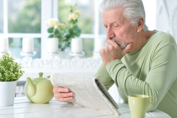 Emotional senior man  reading newspaper