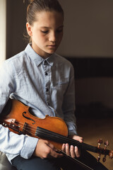 Portrait of teenage violin player sitting on the window and looking unmotivated. Unhappy student...