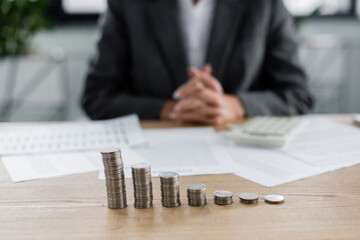 stacks of silver coins near cropped banker sitting on blurred background.