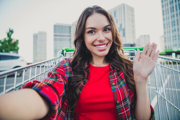 Self-portrait of attractive trendy cheerful carefree girl sitting in cart having fun on parking waving hello outdoors