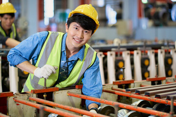 Asian worker male smile on working at heavy machine in matal sheet factory