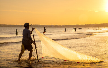 Muine, Binh Thuan Beach, Vietnam - October 31 2015: Vietnamese fishermen sort out nets with caught fish in Binh Thuan Beach in sunrise morning at Vietnam