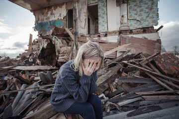 young girl screams against the background of a destroyed house. looks at the camera. military actions