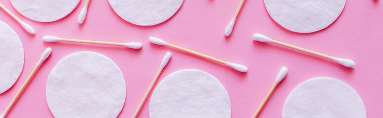 top view of cosmetic cotton pads and hygienic ear sticks on pink background, banner.