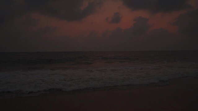 Wide angle slow motion shot of Calangute beach during the sunset with clouds above the ocean at North Goa in Goa, India. Clouds above the sea waves with dramatic sky after the sunset. Beach Background