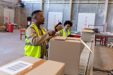 African american young man with young female coworker packaging cardboard box with adhesive tape