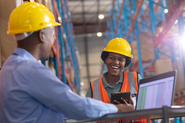 African american young woman holding digital pc laughing while talking with male worker using laptop