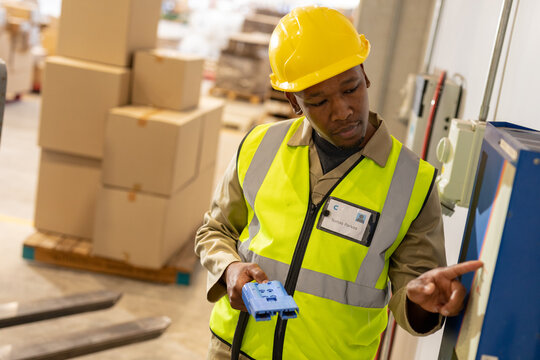 African american young male warehouse worker holding plug operating electric charging equipment
