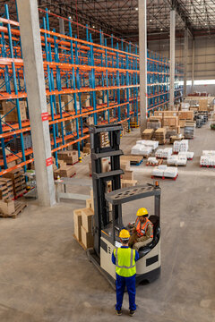 High angle view of asian mature foreman talking with african american young woman driving forklift