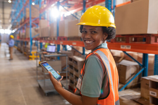 Portrait of smiling confident african american young female warehouse worker using digital tablet - Powered by Adobe