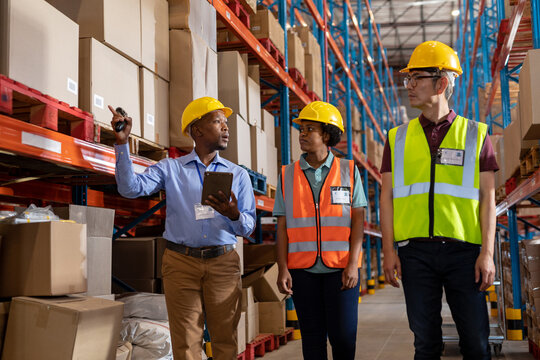 African american young foreman holding digital pc guiding young woman and asian mature male coworker