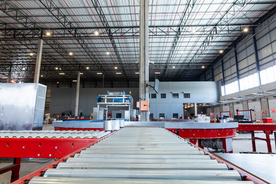 Empty conveyor belt with illuminated lights hanging on ceiling in distribution warehouse