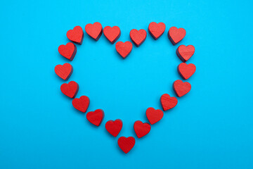 Wooden hearts are laid out in the shape of a heart on a blue background. Top view, flat lay. Place for text. Declaration of love.