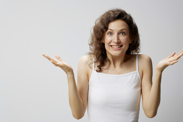 Cheerful surprised excited curly beautiful woman in basic white t-shirt raise hands up won a...