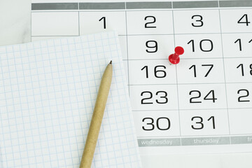 Ballpoint pen, notepad and calendar with date marked. The concept of planning, scheduling, notes on...