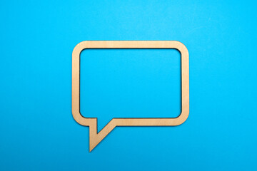 Wooden empty speech bubble concept on blue paper background with drop shadow. Communication concept. Copy space.