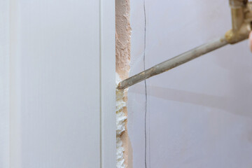 Installing door unit repairman mounting foam the door frame using polyurethane foam a home under...