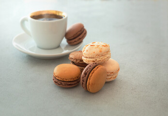 Macaron cake and coffee cup on a gray background with copy space. Confectionery - nut-chocolate macrons. Sweet breakfast, dessert.