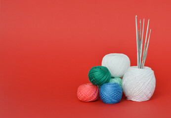 A closeup shot of red, purple, and blue knitting yarns and crochet hooks