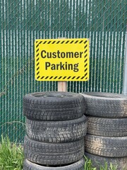 Customer parking sign next to a stack of old worn tires