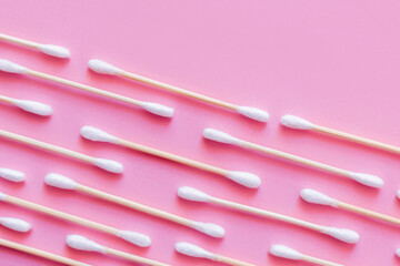 top view of diagonal lines of cotton swabs on pink background.