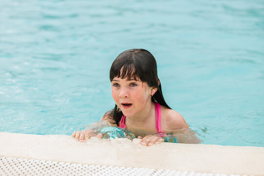 Cute child leaning on pool border and looking away