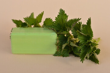 Fototapeta premium A piece of homemade green soap made with your own hands from nettles on a beige backround